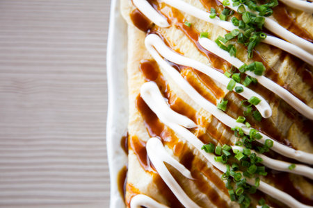 Okonomiyaki is a Japanese omelette filled with vegetables and meat and topped with sauce.