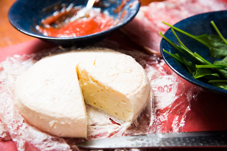 Fresh sheep cheese on a table with ingredients.