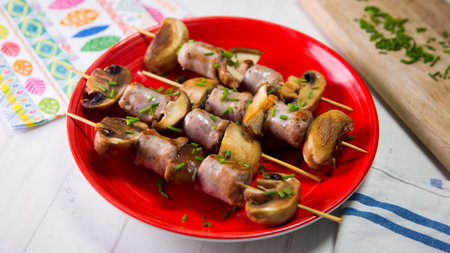 Sausage skewers with mushrooms on red plate.の写真素材