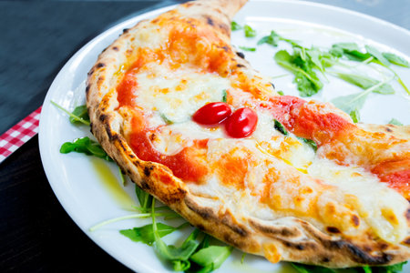 Calzone Pizza. Neapolitan pizza stuffed with cheese, tomato and other ingredients such as meat or...