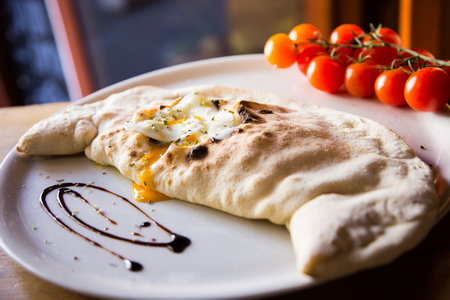 Calzone Pizza. Neapolitan pizza stuffed with cheese, tomato and other ingredients such as meat or vegetables. Authentic Italian recipe.の写真素材