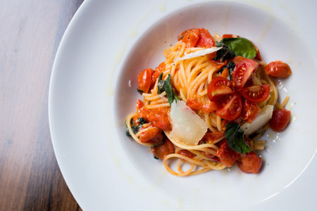 Spaghetti al pomodoro prepared with pasta, olive oil, fresh tomatoes, basil and other fresh...