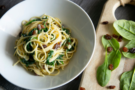 Spaghetti with cream cheese, spinach and raisins.の写真素材