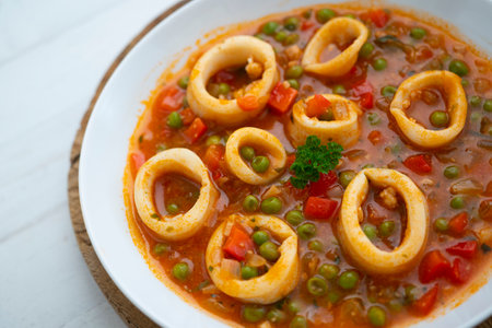 Braised squid rings with tomato and vegetables. Traditional Spanish tapas recipe.
