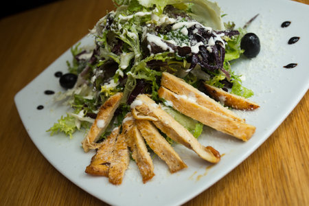 A Caesar salad is a salad of romaine lettuce, croutons, and chicken with lemon juice, olive oil, egg, Worcestershire sauce, anchovies, garlic, Dijon mustard, Parmesan cheese, and bの写真素材