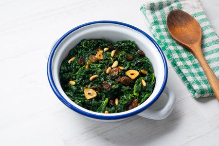 Spinach cooked in a pan with raisins, pine nuts and garlic.