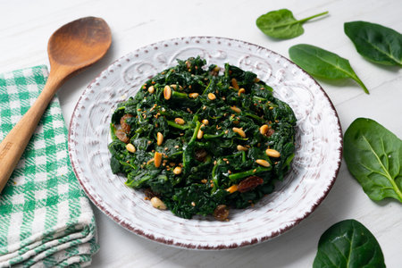 Spinach cooked in a pan with raisins, pine nuts and garlic.の写真素材