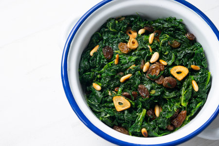 Spinach cooked in a pan with raisins, pine nuts and garlic.の写真素材