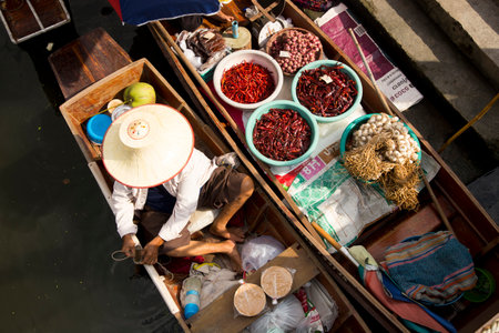 Women selling vegetables and fruit from their canoes at the Tha Kha floating market in Thailandの写真素材