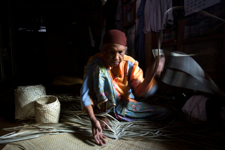 Koh Yao, Thailand; 1st January 2023: Senior woman making a basket with dried palm leaves.のeditorial素材