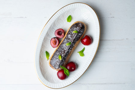 French eclairs filled with chocolate cream and served with fresh cherries.の写真素材
