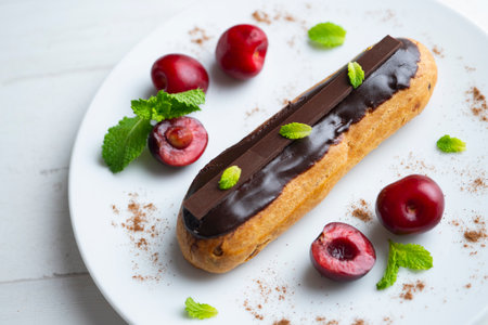 French eclairs filled with chocolate cream and served with fresh cherries.の写真素材