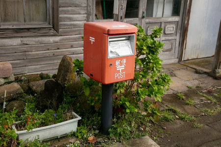 Ogi, Japan; 1st October 2023: Red Japanese mailbox on a street in the city of Oji on the island of...