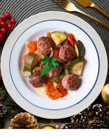 Meat meatballs with tomato sauce and vegetables. Christmas food on a table with decorations.の写真素材