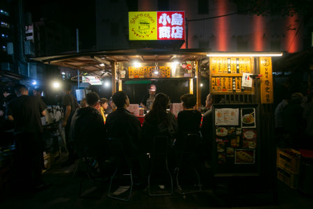 Fukuoka, Japan; 1st October 2023: People eating and drinking in a Yatai in Hakata Bay. A Yatai is a small, mobile food stall in Japan typically selling ramen or other food.のeditorial素材