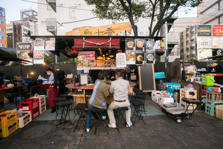Fukuoka, Japan; 1st October 2023: People eating and drinking in a Yatai in Hakata Bay. A Yatai is a small, mobile food stall in Japan typically selling ramen or other food.のeditorial素材