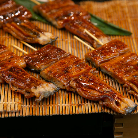 Roasted skewered eel at a food market in the city of Osaka in Japan.の写真素材