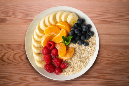 Delicious and healthy bowl of oatmeal with tangerine, banana, blueberries and raspberries.