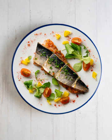 Baked mackerel stuffed with vegetables and tomato. Top view table.の写真素材