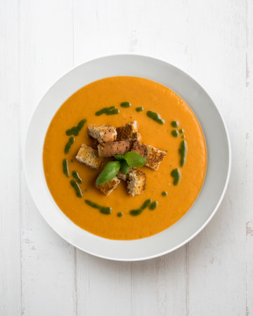Tomato soup with basil oil and croutons. Top view table with decoration.の写真素材