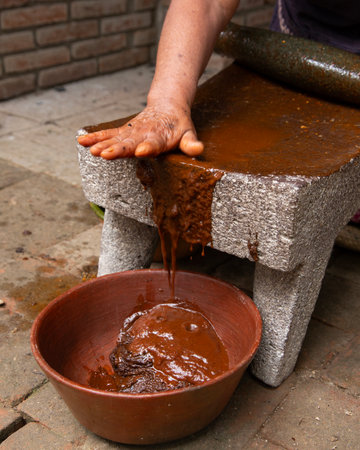 Woman from an indigenous community in Oaxaca preparing traditional Mole Rojo with a metate, a tool for grinding ingredients in Mexico.の写真素材