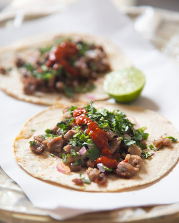 Delicious Mexican tacos with handmade tortillas with beef and spicy red sauce.の写真素材