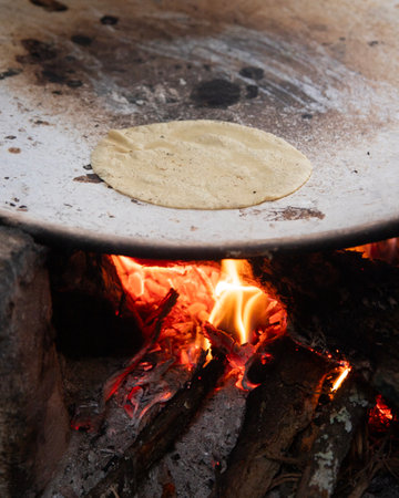 Cooking handmade corn tortillas on a traditional comal in an open fire kitchen in Oaxaca Mexico.の写真素材