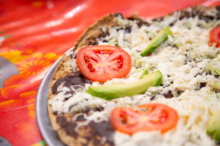 Tlayuda is a thin, crispy tortilla topped with black beans, beef jerky, tomato and avocado. It is a traditional Mexican food from Oaxaca.の写真素材