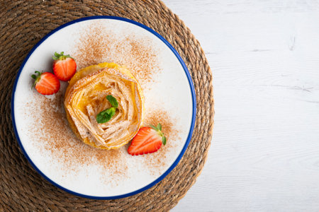 Flower-shaped tart made with filo pastry filled with cream. Top view table.