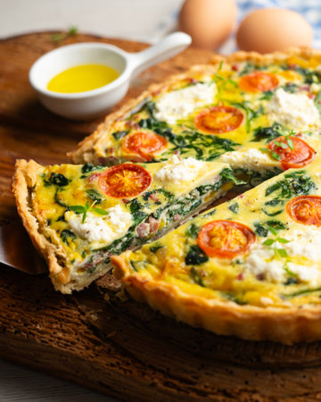 Quiche with spinach, cheese, tomatoes, and diced ham. Traditional recipe.の写真素材