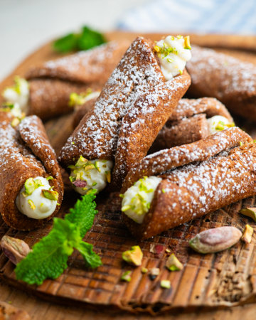 Sicilian cannoli filled with ricotta cheese cream and topped with chopped pistachios.