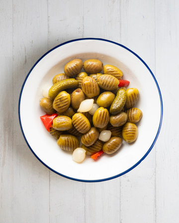 White plate with grilled olives, onions, peppers, and pickles. Overhead view of the table.の写真素材