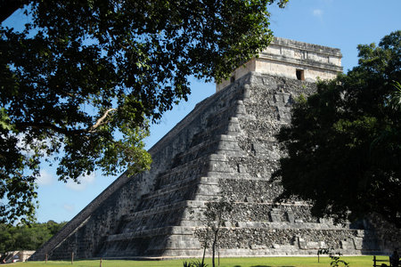 The iconic El Castillo pyramid, also known as the Temple of Kukulcan, stands majestically against a...