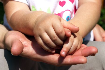 Women's hand holding little baby' handsの写真素材