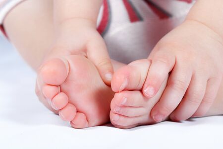 Baby feet with hands on white background