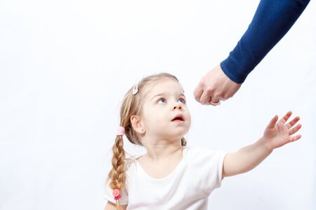 Little blonde baby girl grabs hand for items provided by her mother's handの写真素材