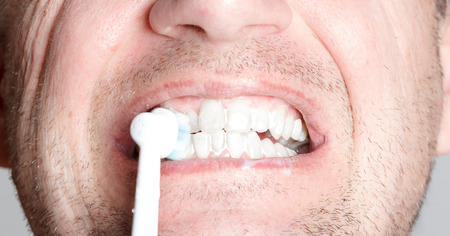 Close-up of a young man while brushing his teeth, personal hygiene