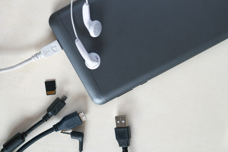 Phone accessories, usb cables, headphones on a white wood background