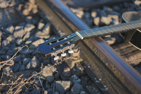 Old classic guitar laid down on railway pathの写真素材