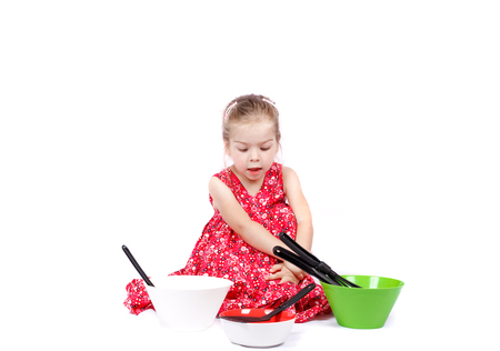 Adorable caucasian little girl isolated on whit background, cooking with silver and coloured potの写真素材