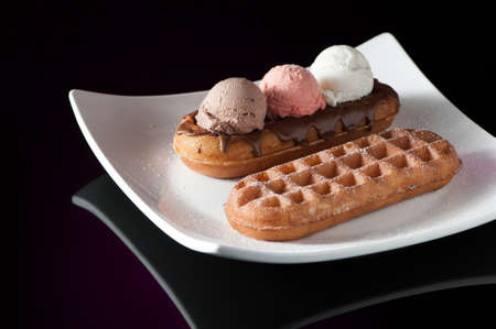 Waffles and ice cream in a dish on a dark background