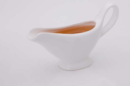 sauce in white gravy boat on a white backgroundの写真素材