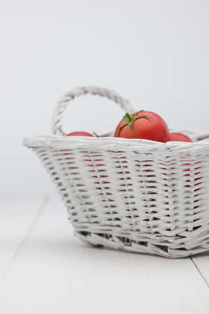 tomatoes in a white basket on a white backgroundの写真素材