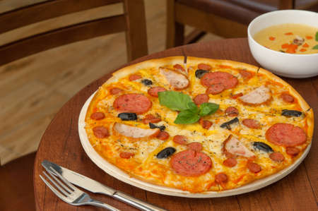 pizza on the kitchen table with a fork and soupの写真素材