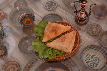 bun with salad in a wicker plate on a surface of glass on the background of the set of cups and...