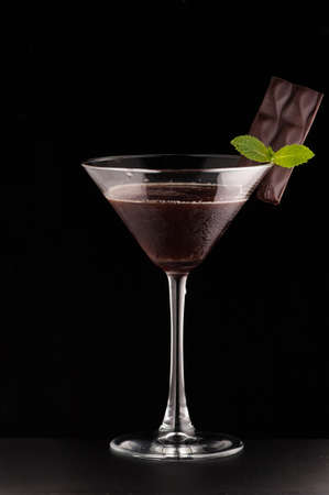 one glass cup with a drink and chocolate on a dark backgroundの写真素材