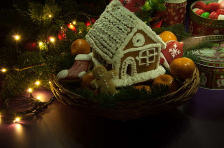New Year Christmas cookies with tangerines and a small house in the basket next to the Christmas tree branch and toysの写真素材