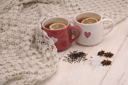 two cups of tea with lemon and scarf on wooden boardsの写真素材