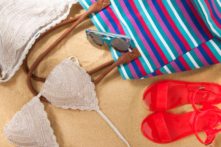 set of bright summer clothes for the beach on the golden sandの写真素材