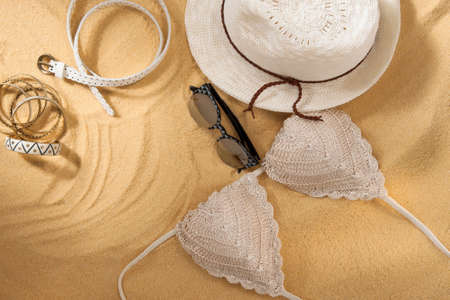 set of bright summer clothes for the beach on the golden sandの写真素材